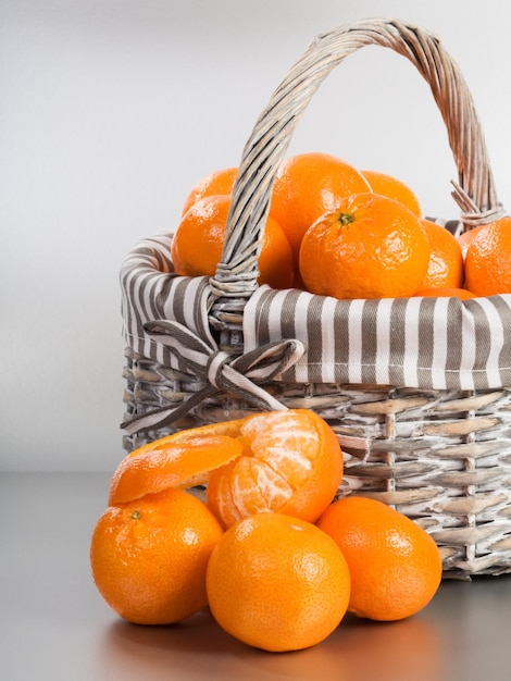 Basket and stack of fresh tangerines on silver background