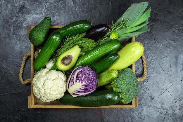 Foto un cesto di verdure tra cui cetrioli, cavoli e cavolfiori.