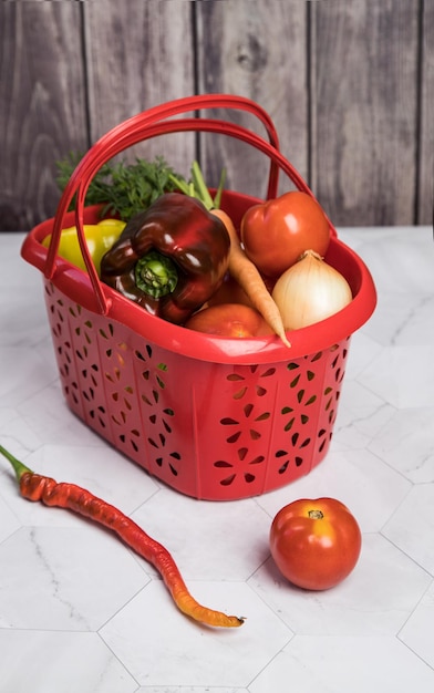 Basket with autumn harvest of vegetables tomatoes onions peppers on a light background