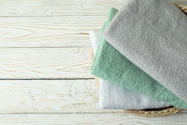 Basket with clean towels on white wooden table