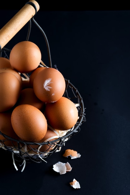 Basket with close up fresh farm natural chicken eggs on a black surface. Easter congratulation card.