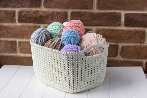 Basket with coils of plush yarn in pastel colors Knitter's basket on a white table