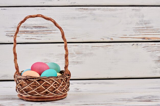 Basket with colored eggs Wicker basket on wooden background Simple Easter breakfast