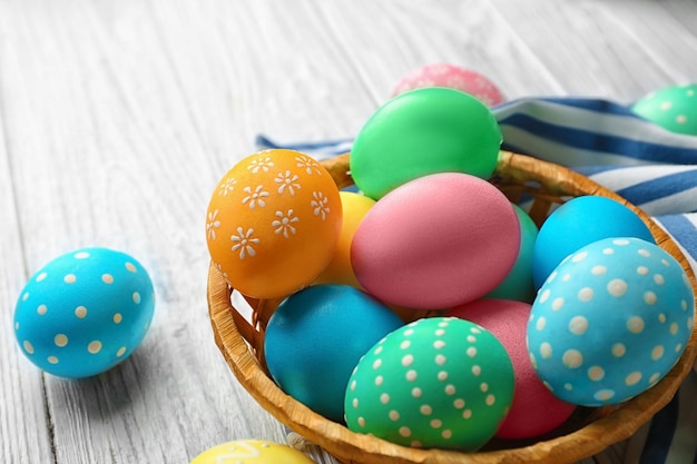 Basket with colorful Easter eggs on wooden table closeup