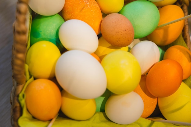 Photo basket with colorful eggs on agricultural farm market, top view, close up