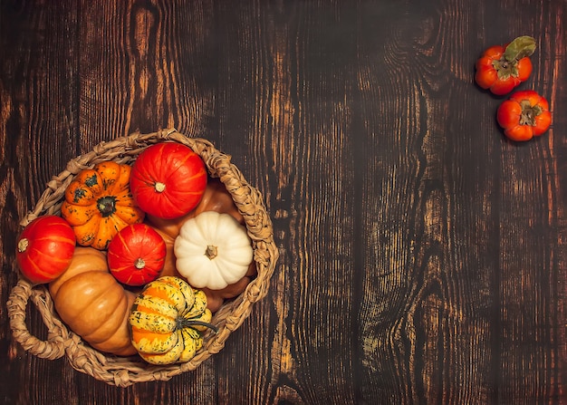 Basket with different varieties of pumpkin on a wooden background top view flatlay