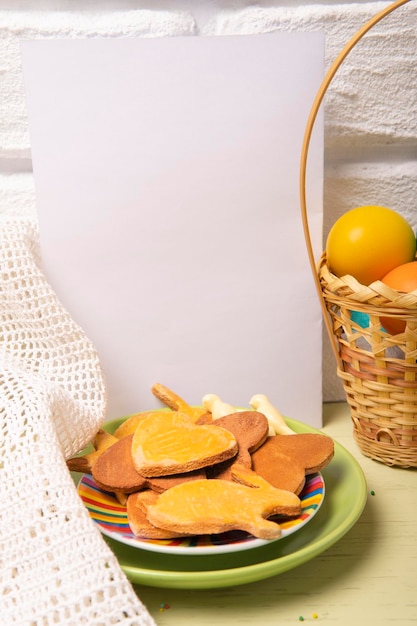 Basket with Easter colored eggs plate with holiday cookies and white empty paper card