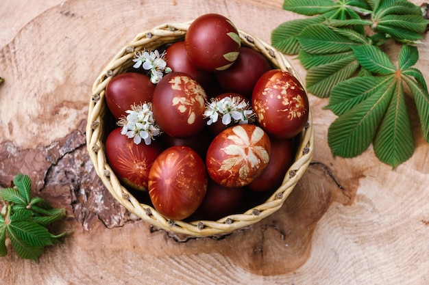 Cestino con uova rosse di pasqua su tavola in legno rustico
