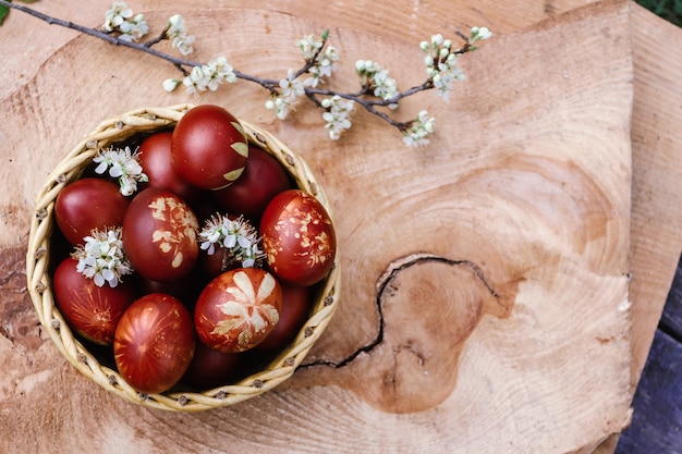 Cestino con uova rosse di pasqua su tavola in legno rustico