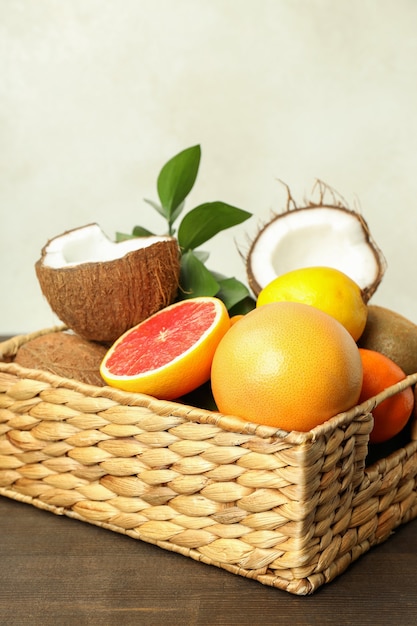 Basket with exotic fruits on wooden table.