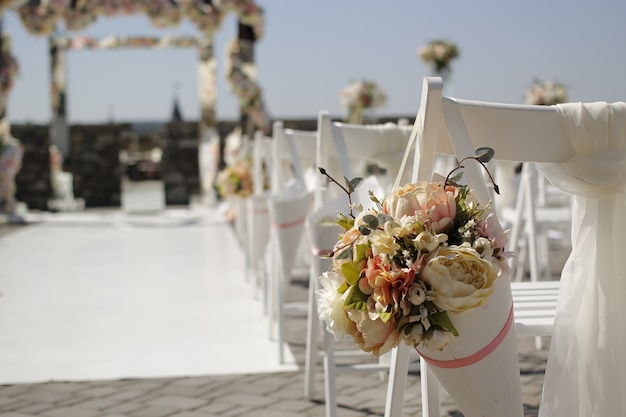 Корзина с цветами на спинке стула на свадебной церемонии, выборочный фокус