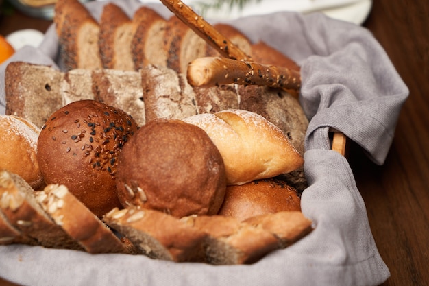 Basket with fresh bread on wooden table background. Variety of bakery bread products in basket