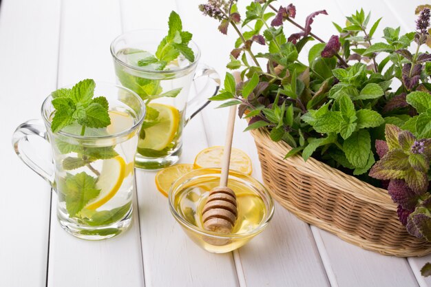 Basket with fresh green mint and two glass cups with fresh mint tea on white  table