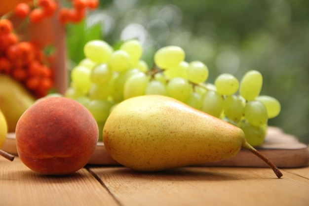 Basket with fresh and juicy fruits and berries on a wooden table closeup Pears rowan and grapes in a wooden basket on a blurred background