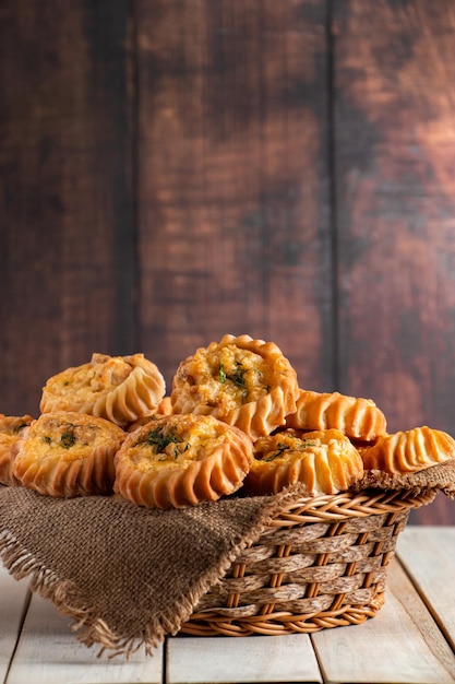 Basket with fresh muffins on wooden background homemade cakes\
with vegetables and cheese recipe for autumn seasonal dish