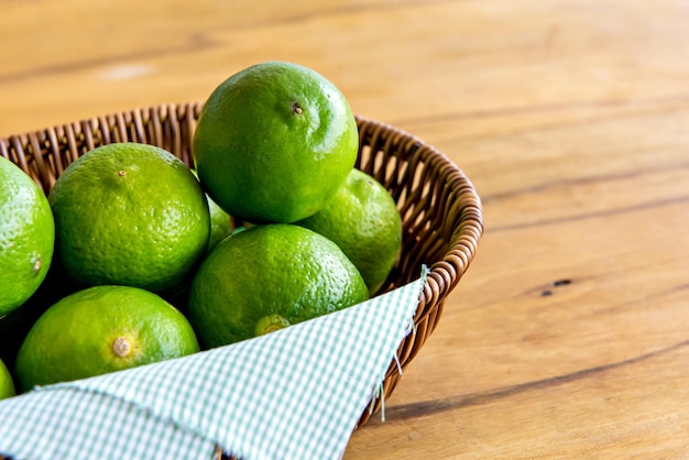 Basket with green lemons on a wooden table