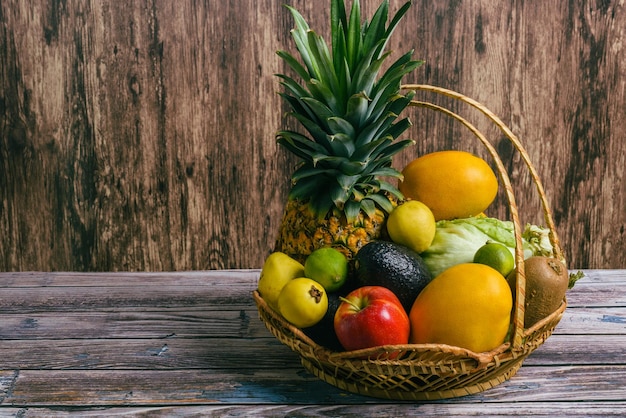 Basket with a group of different fruits on a wooden table Wicker basket with ripe fruits