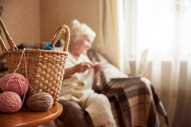 Basket with knitting needles and woolen yarn