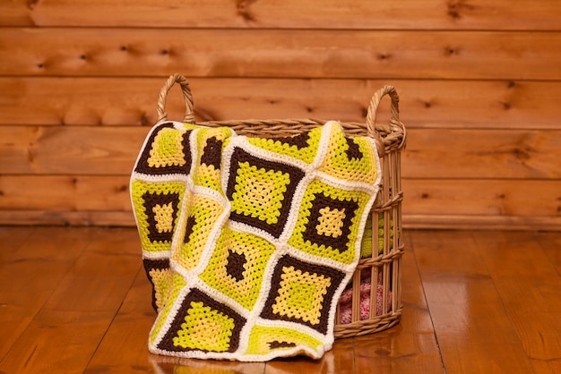 Basket with a patchwork plaid on the background of a wooden wall Granny square crochet