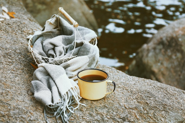 Basket with plaid and mug on rock in the forest close up