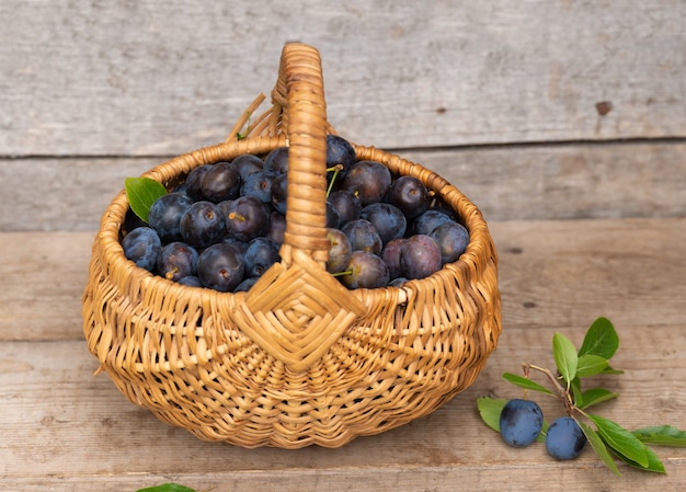 Basket with plums on a wood