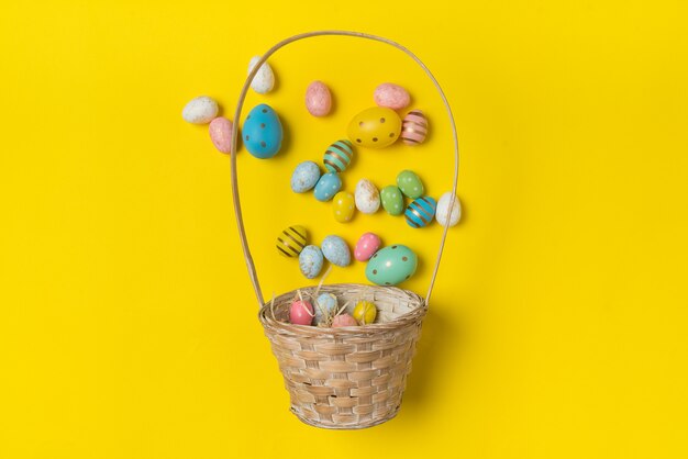 Basket with scattered Easter eggs. Festive eggs. Bright yellow background, top view