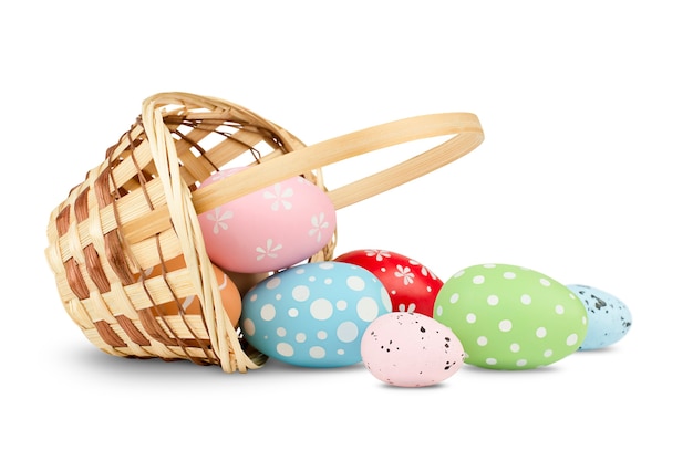 Basket with scattered easter eggs on isolated white wall