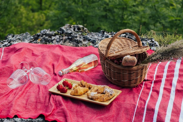 Basket with summer flowers and baguette wooden tray with croissants and strawberry and white wine