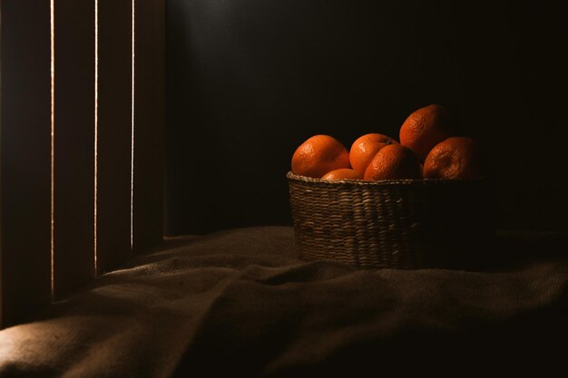 Basket with tangerines on table dark background