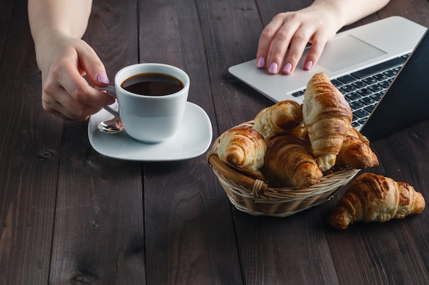 Foto cesto con gustosi cornetti freschi e calda tazza di caffè al mattino