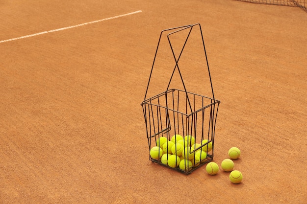 Foto cestino con palline da tennis su campo in terra battuta