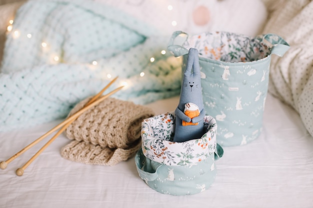 basket with toys yarn needles knitted clothes against bokeh lights surface in a cozy nursery