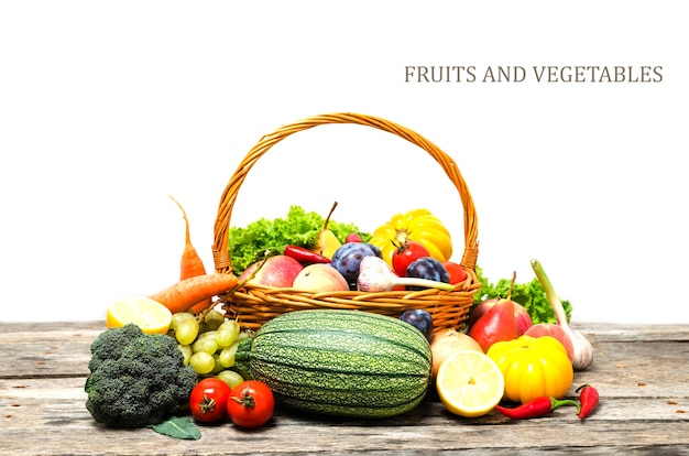 Foto cesto con frutta e verdura sul tavolo di legno, su sfondo bianco.vitamine utili.