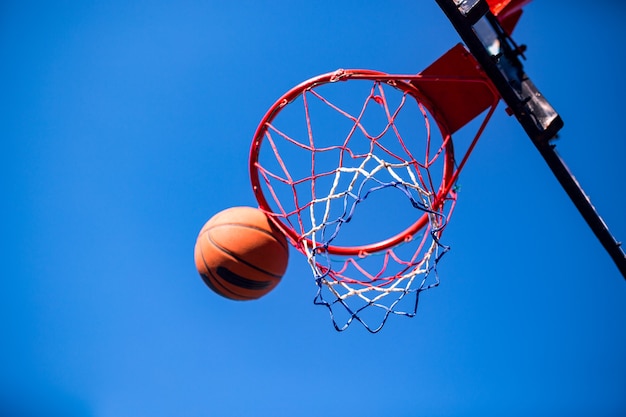 Basketbal bal en hoepel geïsoleerd op blauwe hemel