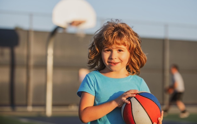 Basketbal kinderspel portret van schattige kleine jongen die een basketbalbal vasthoudt en probeert te scoren