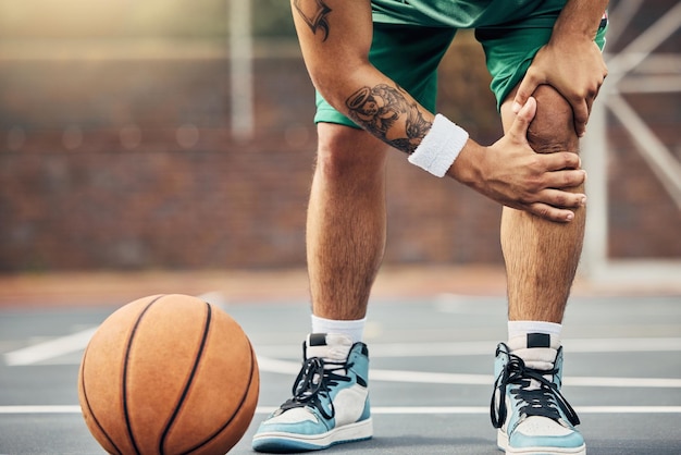 Basketball athlete and knee injury on the basketball court during outdoor game or training Man in with leg pain after sports accident with a broken joint inflammation or muscle tear during match