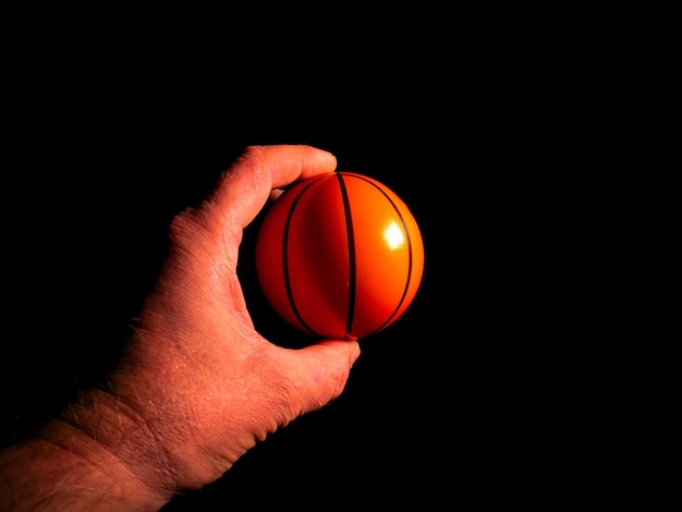 Photo basketball ball in hand on a black background