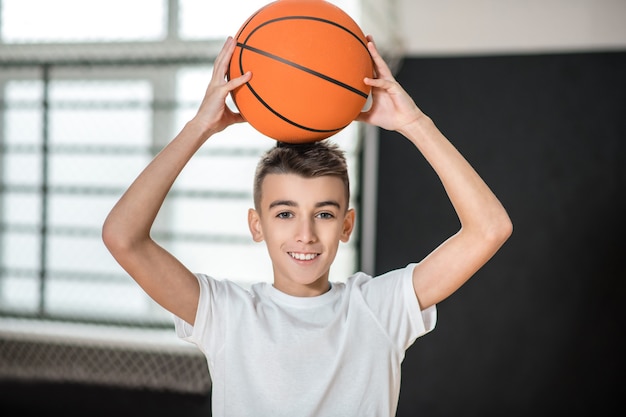 Basketball. A cute boy with a ball feeling good and contented