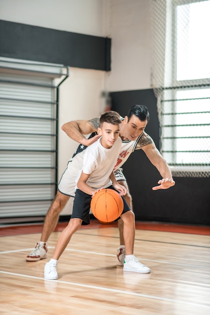 バスケットボール。男の子とバスケットボールをしている黒髪の男