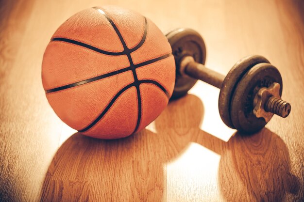 Photo basketball and dumbbell on hardwood floor