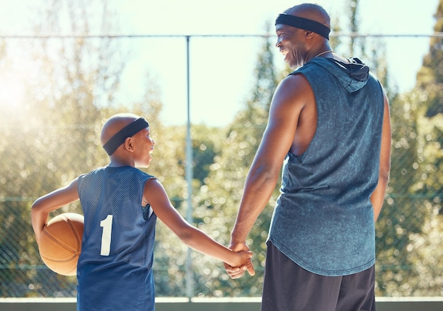 Foto famiglia di basket e sport con un papà e un figlio che si allenano su un campo all'aperto per fitness e divertimento i bambini si esercitano e si allenano con un padre e un ragazzo che giocano a basket per la salute e la ricreazione