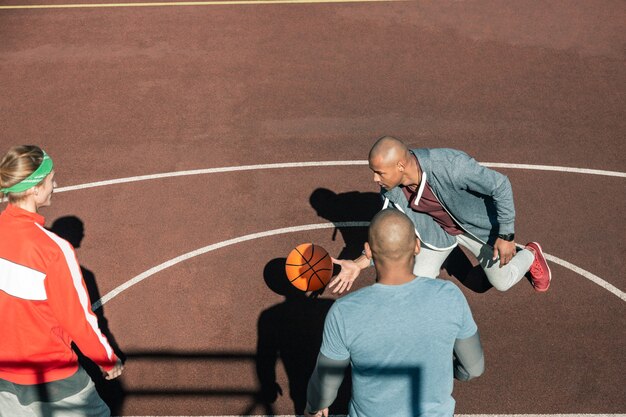 Basketball game. Top view of pleasant young men catching the ball while playing basketball