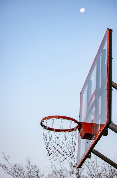 Basketball hoop background blurry tree and moon in the sky.