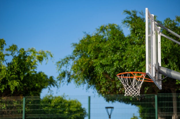 Foto canestro da basket in una limpida giornata di sole con alberi