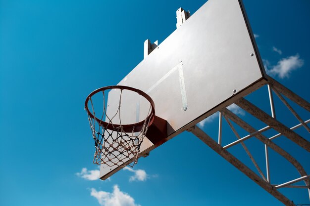 Basketball hoop in sunny day of autumn on background of blue sky