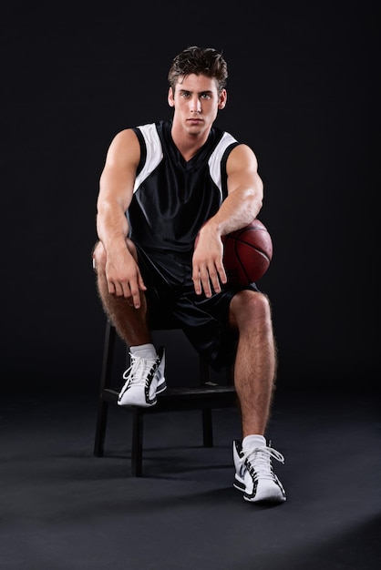 Basketball is his thing Full length studio portrait of a male basketball player sitting with the ball under his arm