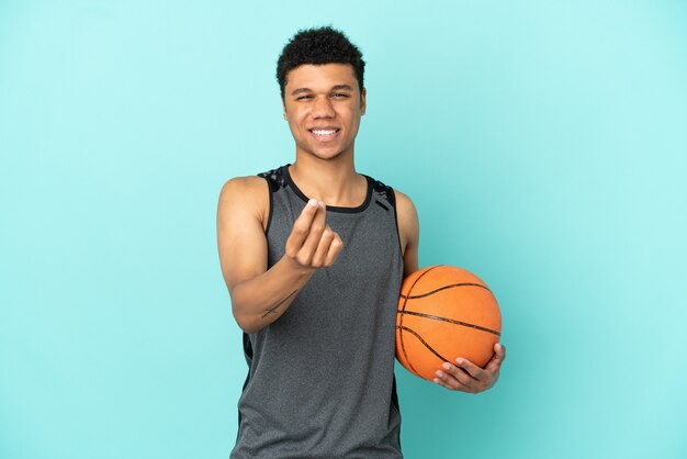 Basketball player african american man isolated on blue\
background making money gesture