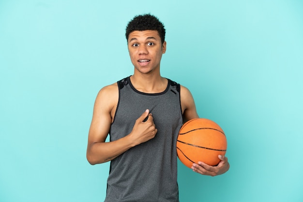 Basketball player African American man isolated on blue background with surprise facial expression