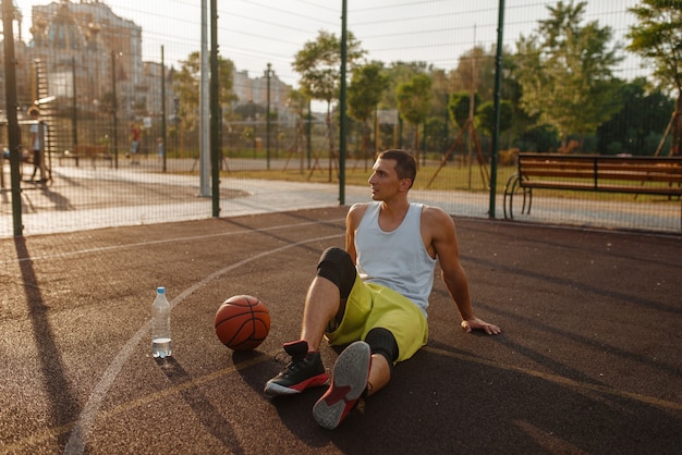 写真 バスケットボール選手は屋外コートで水を飲む