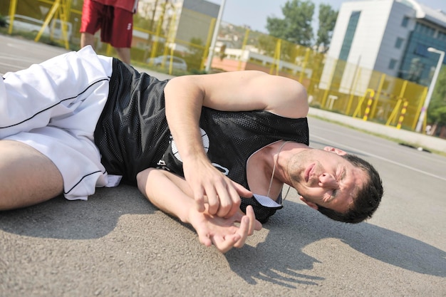 Il giocatore di basket ha un trauma al piede e un infortunio al campo da streetbal all'aperto